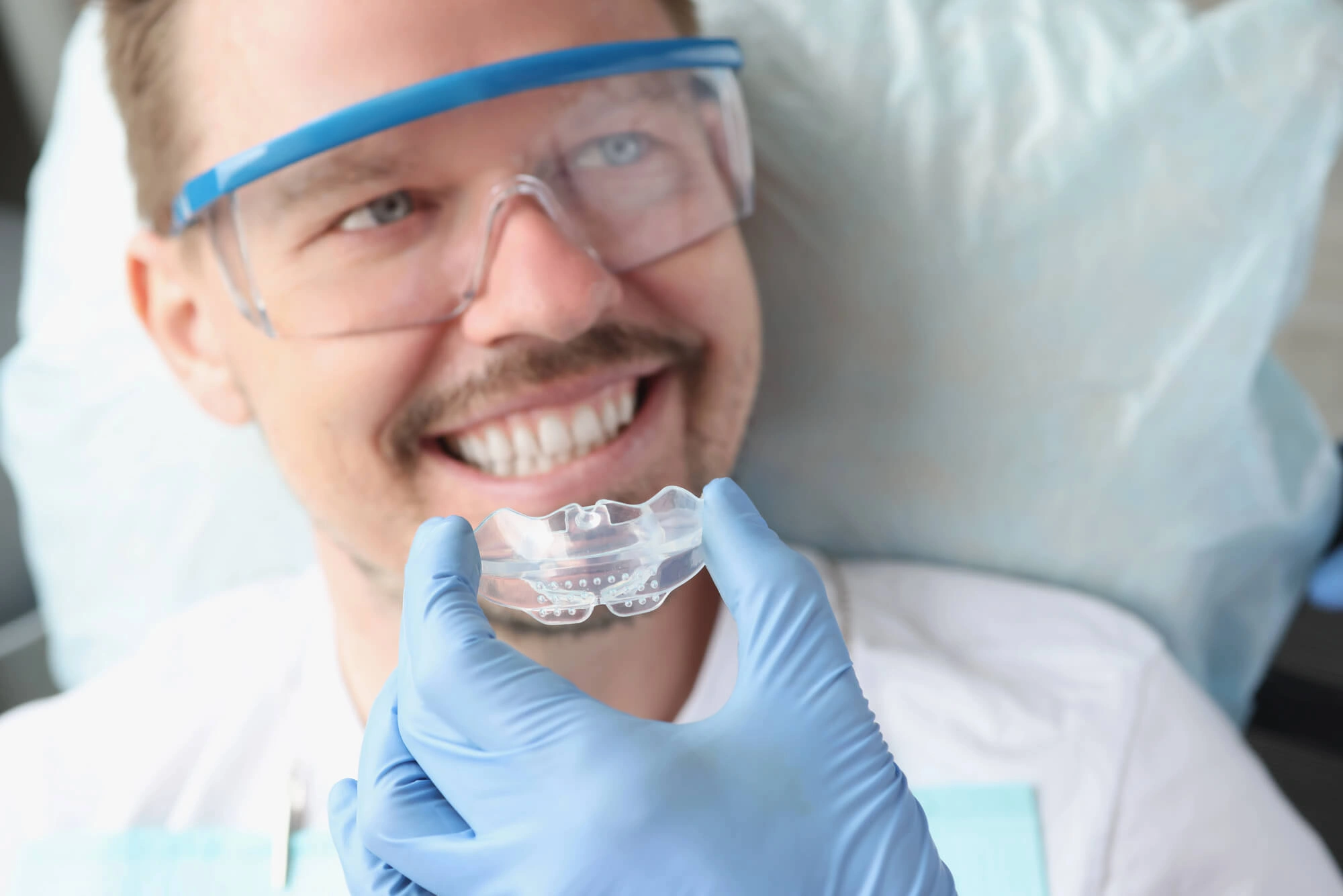Orthodontist Clawson putting mouthguard on patient